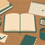 Open textbook, notebook, and laptop arranged for organized college study session on a desk