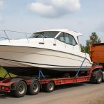 Secure boat being lifted by crane onto transport trailer, demonstrating safe boat transfer techniques
